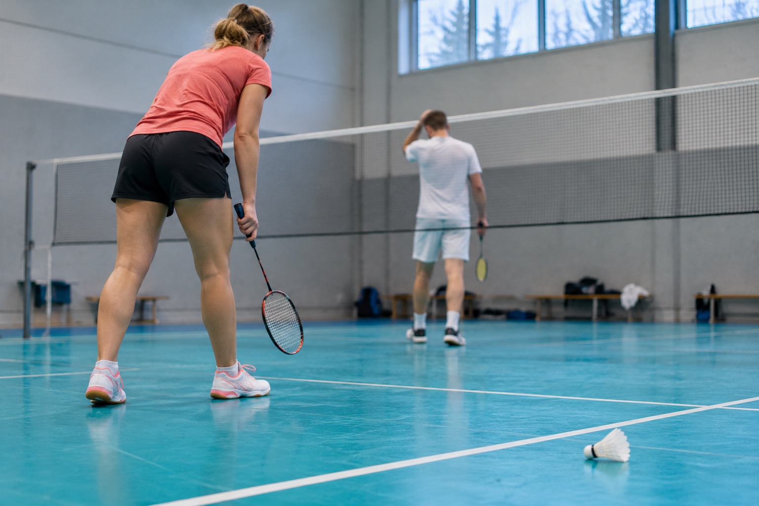 Fiktive badmintonspillere på en turkis træningsbane; ikke Christiansen, Bøje eller et foto fra French Open. AI-genereret, fotorealistisk temabillede; viser ikke den konkrete begivenhed.