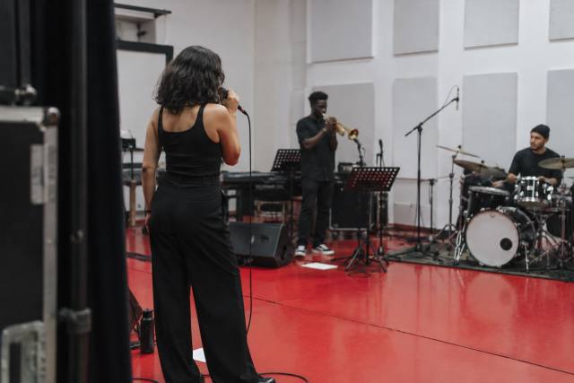 Fiktiv sanger og musikere på en rød prøvescene; ikke RAYE, hendes band eller et foto fra Mercury Prize. AI-genereret, fotorealistisk temabillede; viser ikke den konkrete begivenhed.